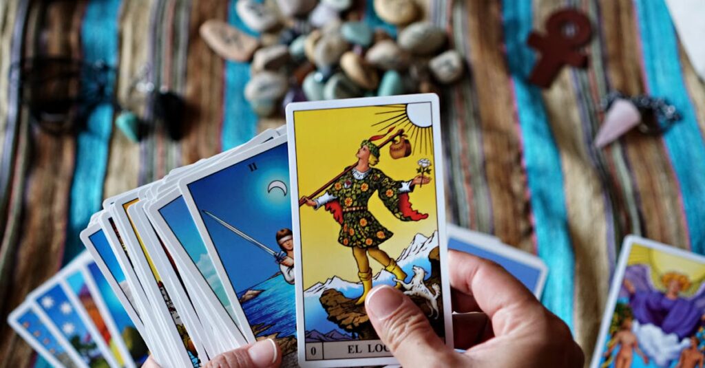 Hands holding tarot cards over a vibrant striped cloth with stones and charms, creating a spiritual atmosphere.