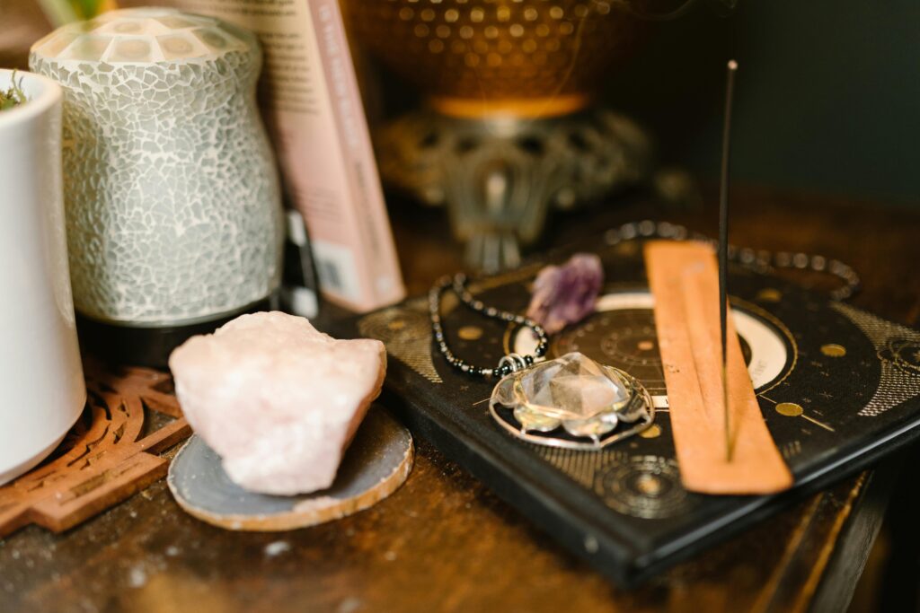 Warm-toned composition featuring incense, rose quartz, and mystical elements on a wooden surface.